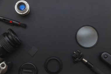 DSR kamera sistemi olan fotoğrafçı işyeri, kamera temizleme seti, siyah masa arka planında lens ve kamera aksesuarı. Hobi seyahat fotoğrafçılık konsepti. Düz görünüm kopyalama alanı