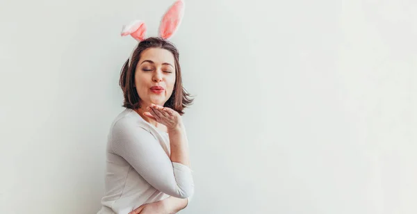 ハッピーイースターのお祝い春のコンセプト 白い背景にウサギの耳を身に着けている若い女性 休日の準備 女の子は幸せと興奮して イースターの日に楽しんでいます バナー — ストック写真
