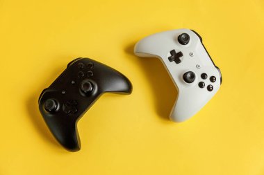 Beyaz ve siyah iki joystick Gamepad, sarı renkli şık modern moda pin-up arka planda oyun konsolu. Bilgisayar oyun Yarışması videogame kontrol çatışma kavramı. Siber uzay sembolü