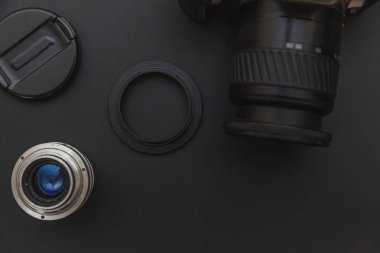 Karanlık masa arka planında DSR kamera sistemi ve lensleri olan fotoğrafçı işyeri. Hobi seyahat fotoğrafçılık konsepti. Düz görünüm kopyalama alanı