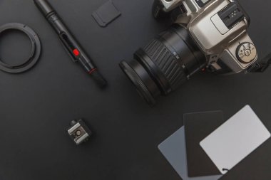 DSR kamera sistemi olan fotoğrafçı işyeri, kamera temizleme seti, siyah masa arka planında lens ve kamera aksesuarı. Hobi seyahat fotoğrafçılık konsepti. Düz görünüm kopyalama alanı