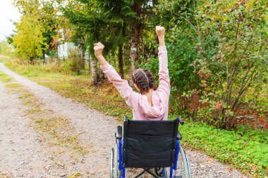 Hastane parkında tekerlekli sandalyedeki mutlu engelli kadın özgürlüğün tadını çıkarıyor. Doğadaki engelli insanlar için sakat sandalyeli felçli bir kız. Rehabilitasyon kavramı