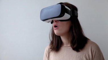 Beyaz arka planda sanal gerçeklik gözlüğü başlığı takan genç kadın gülümse. Sanal gerçeklik gözlüğü takan akıllı telefon. Teknoloji, simülasyon, yüksek teknoloji, video oyunu konsepti