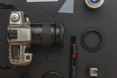 DSR kamera sistemi olan fotoğrafçı işyeri, kamera temizleme seti, siyah masa arka planında lens ve kamera aksesuarı. Hobi seyahat fotoğrafçılık konsepti. Düz görünüm kopyalama alanı.