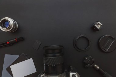 DSR kamera sistemi olan fotoğrafçı işyeri, kamera temizleme seti, siyah masa arka planında lens ve kamera aksesuarı. Hobi seyahat fotoğrafçılık konsepti. Düz görünüm kopyalama alanı.