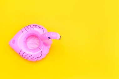 Yaz kumsalı kompozisyonu. Sarı arka planda pembe şişirilebilir flamingo ile basit bir tasarım. Havuz şamandırası partisi, ünlü modası konsepti. Düz görünüm kopyalama alanı.