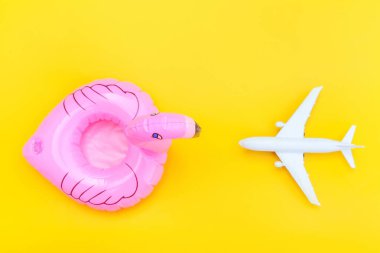 Yaz kumsalı kompozisyonu. Uçak ve sarı zemin üzerinde izole edilmiş şişirilebilir flamingo ile minimum basit düz yatıyordu. Seyahat macerası konsepti. Üst görünüm kopyalama alanı.