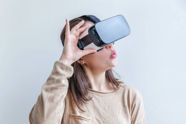 Beyaz arka planda sanal gerçeklik gözlüğü başlığı takan genç kadın gülümse. Sanal gerçeklik gözlüğü takan akıllı telefon. Teknoloji, simülasyon, yüksek teknoloji, video oyunu konsepti