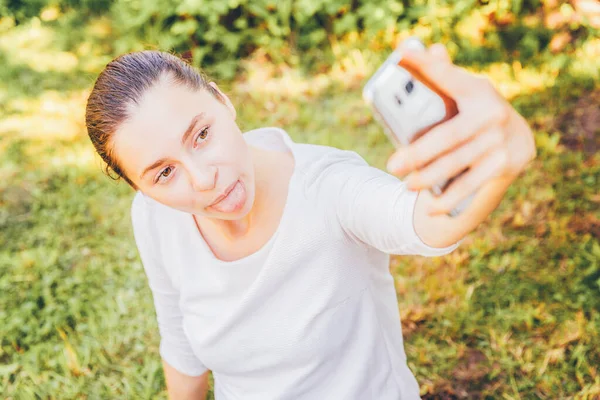 Menina Tirar Selfie Mãos Com Telefone Mostrando Língua Rosto Engraçado — Fotografia de Stock