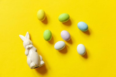 Mutlu Paskalyalar. Tatil için hazırlık. Paskalya çikolatalı yumurta, tatlı ve sarı arka planda izole edilmiş tavşan oyuncağı. Basit minimalizm düz üst görünüm kopyalama alanı