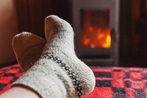 脚腿穿着冬衣 毛袜在壁炉前 冬天或秋天的晚上 女人坐在家里休息和热身 冬季和寒冷天气的概念 Hygge圣诞前夕 — 图库照片