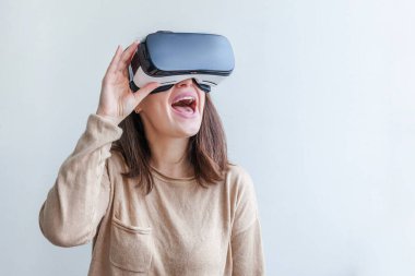 Beyaz arka planda sanal gerçeklik gözlüğü başlığı takan genç kadın gülümse. Sanal gerçeklik gözlüğü takan akıllı telefon. Teknoloji, simülasyon, yüksek teknoloji, video oyunu konsepti