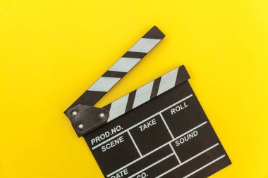 Film yapımcılığı mesleği. Klasik yönetmen boş film klapperboard ya da film tahtası sarı arka planda izole edilmiş. Video yapım film endüstrisi konsepti. Düz görünüm fotokopi alanı maketi