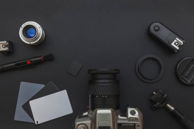 DSR kamera sistemi olan fotoğrafçı işyeri, kamera temizleme seti, siyah masa arka planında lens ve kamera aksesuarı. Hobi seyahat fotoğrafçılık konsepti. Düz görünüm kopyalama alanı