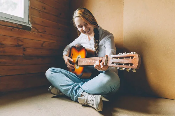 Stay Home Stay Safe. Young woman sitting in room on floor and playing guitar at home. Teen girl learning to play song and writing music. Hobby lifestyle relax Instrument leisure education concept
