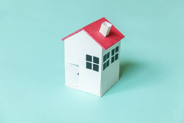 Mavi pastel renkli arka planda izole edilmiş minyatür beyaz oyuncak evi olan basit bir tasarım. Ev kredisi sigortası hayali ev konsepti. Düz görünüm kopyalama alanı