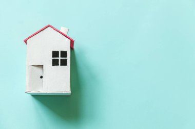 Mavi pastel renkli arka planda izole edilmiş minyatür beyaz oyuncak evi olan basit bir tasarım. Ev kredisi sigortası hayali ev konsepti. Düz görünüm kopyalama alanı