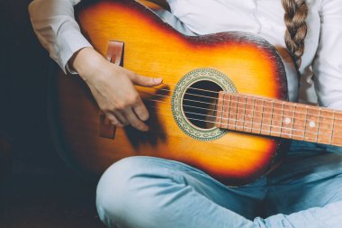 Evde kal. Kendine dikkat et. Genç bir kadın evde oturup gitar çalıyor, elleri yakın. Genç kız şarkı çalmayı ve şarkı yazmayı öğreniyor. Hobi yaşam tarzı rahatla Enstrüman eğlence eğitimi konsepti