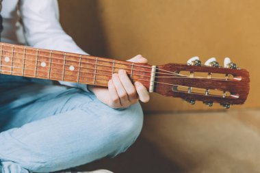 Evde kal. Kendine dikkat et. Genç bir kadın evde oturup gitar çalıyor, elleri yakın. Genç kız şarkı çalmayı ve şarkı yazmayı öğreniyor. Hobi yaşam tarzı rahatla Enstrüman eğlence eğitimi konsepti