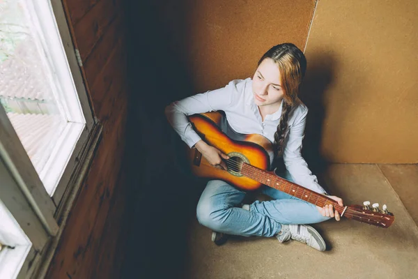 Stay Home Stay Safe. Young woman sitting in room on floor and playing guitar at home. Teen girl learning to play song and writing music. Hobby lifestyle relax Instrument leisure education concept