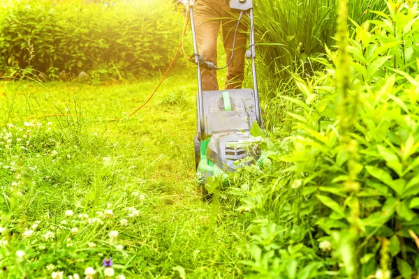 Homme coupant l'herbe verte avec tondeuse à gazon dans la cour. Jardinage campagne style de vie arrière-plan. Belle vue sur pelouse d'herbe verte fraîche au soleil, paysage de jardin au printemps ou en été. — Photo