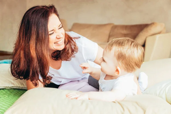 Stay Home Stay Safe. Young mother holding her child. Woman and infant little girl relaxing in white light bedroom indoors. Happy family at home. Young mom playing whith her daughter. — Stock Photo, Image