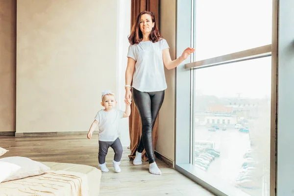 Restez à la maison Restez en sécurité. Jeune mère tenant son enfant. Femme et petite fille se détendant dans une chambre blanche près de windiow à l'intérieur. Bonne famille à la maison. Jeune maman jouant whith sa fille . — Photo