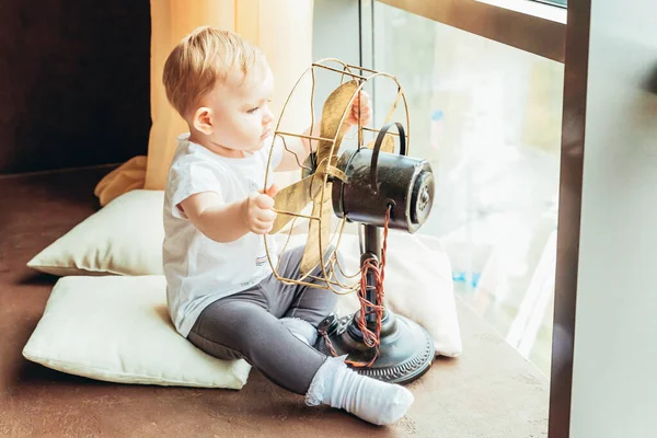 Fica em casa em segurança. Pequena menina bebê bebê doce bonito sentado com ventilador perto de grande janela na sala de estar de luz brilhante em casa dentro de casa. Conceito de ternura maternidade da família da infância . — Fotografia de Stock