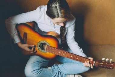 Evde kal. Kendine dikkat et. Genç bir kadın yerde oturuyor ve evde gitar çalıyor. Genç kız şarkı çalmayı ve şarkı yazmayı öğreniyor. Hobi yaşam tarzı rahatla Enstrüman eğlence eğitimi konsepti