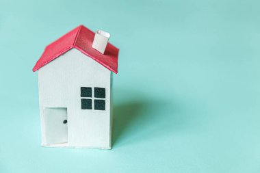 Mavi pastel renkli arka planda izole edilmiş minyatür beyaz oyuncak evi olan basit bir tasarım. Ev kredisi sigortası hayali ev konsepti. Düz görünüm kopyalama alanı