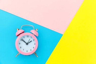 Çalan ikiz çan klasik alarm saati mavi pembe renkli renkli geometrik arkaplanda izole edilmiş. Hayatın dinlenme saatleri. İyi sabahlar. Uyanık kalma kavramı. Düz görünüm kopyalama alanı