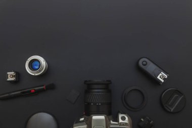 DSR kamera sistemi olan fotoğrafçı işyeri, kamera temizleme seti, siyah masa arka planında lens ve kamera aksesuarı. Hobi seyahat fotoğrafçılık konsepti. Düz görünüm kopyalama alanı
