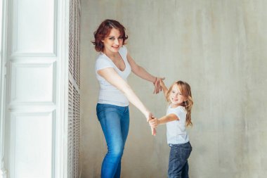 Evde kal. Kendine dikkat et. Genç anne çocuğunu kucağında tutuyor. Kadın ve küçük kız, içerideki pencerenin yanındaki beyaz yatak odasında dinleniyorlar. Evde mutlu bir aile. Genç anne kızıyla oynuyor.