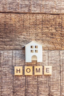Evde kal. Kendine dikkat et. Tahta arka planda ev harfleri yazılı minyatür oyuncak evi. Sosyal uzaklık farkındalığı. Güzel ev COVID-19 Coronavirus karantina konsepti