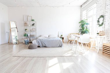 Evin içinde şık bir çatı katı var. Geniş duvarları, geniş pencereleri, büyük yatağı olan geniş bir tasarım dairesi. Minimalist İskandinav tarzında zarif mobilyalarla temiz modern dekorasyon.
