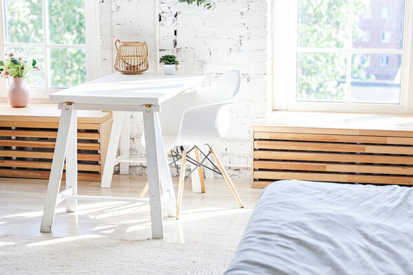 Stylish loft modern home office interior. Spacious design apartment with light walls large windows and writing desk. Clean modern decoration with elegant furniture in minimalist Scandinavian style
