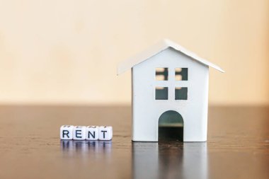 Minyatür oyuncak model evi. Üzerinde tahta zemin üzerine yazılmış RENT harfleri var. Eco Village soyut çevre geçmişi. Gayrimenkul ipoteği sigortası tatlı ev ekoloji kira kavramı