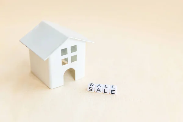 Miniature toy model house with inscription SALE letters word on wooden backdrop. Eco Village abstract environmental background. Real estate mortgage property insurance sweet home ecology rent concept