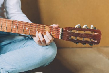 Evde kal. Kendine dikkat et. Genç bir kadın evde oturup gitar çalıyor, elleri yakın. Genç kız şarkı çalmayı ve şarkı yazmayı öğreniyor. Hobi yaşam tarzı rahatla Enstrüman eğlence eğitimi konsepti