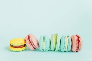Tatlı badem rengi pembe mavi sarı badem kurabiyesi ya da modayı takip eden mavi pastada izole edilmiş badem kurabiyesi. Fransız kurabiyesi. Asgari gıda fırını konsepti. Düz görünüm kopyalama alanı