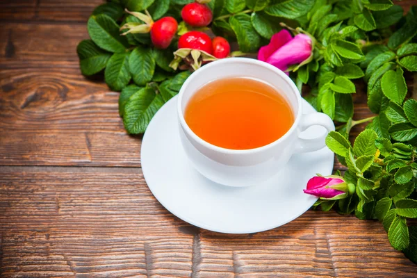 Gesunder Tee mit Heckenrose auf Holztisch — Stockfoto