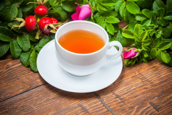 Gesunder Tee mit Heckenrose auf Holztisch — Stockfoto