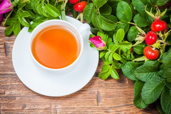 Té saludable con un escaramujo en la mesa de madera —  Fotos de Stock