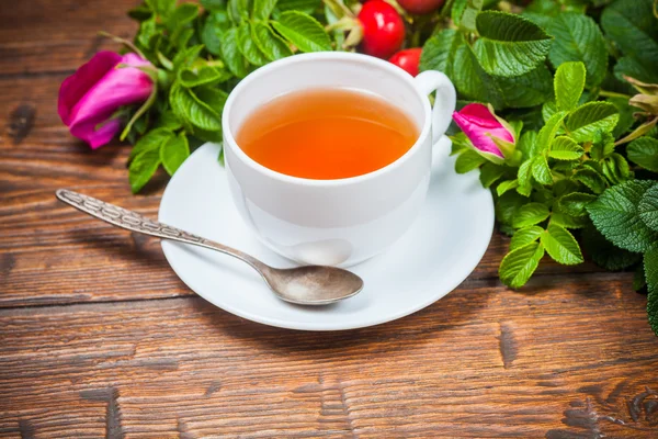 Chá saudável com uma rosa brava na mesa de madeira — Fotografia de Stock