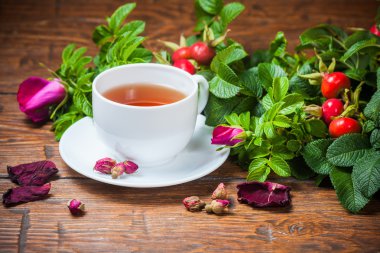 Ahşap masa üzerinde bir dogrose ile sağlıklı çay