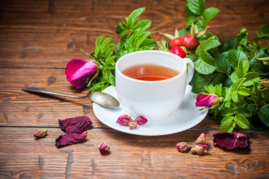 Ahşap masa üzerinde bir dogrose ile sağlıklı çay