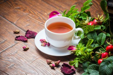 Ahşap masa üzerinde bir dogrose ile sağlıklı çay