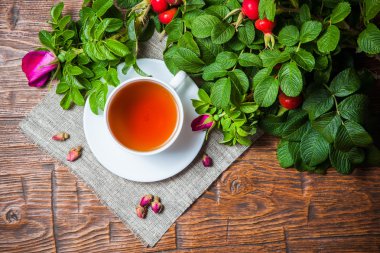 Ahşap masa üzerinde bir dogrose ile sağlıklı çay