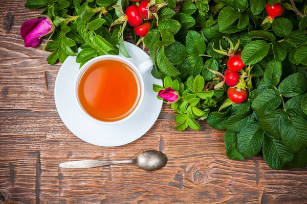 Gesunder Tee mit Heckenrose auf Holztisch — Stockfoto