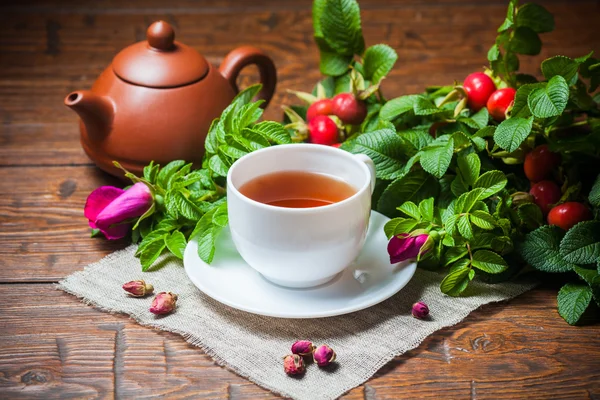 Chá saudável com uma rosa brava na mesa de madeira — Fotografia de Stock